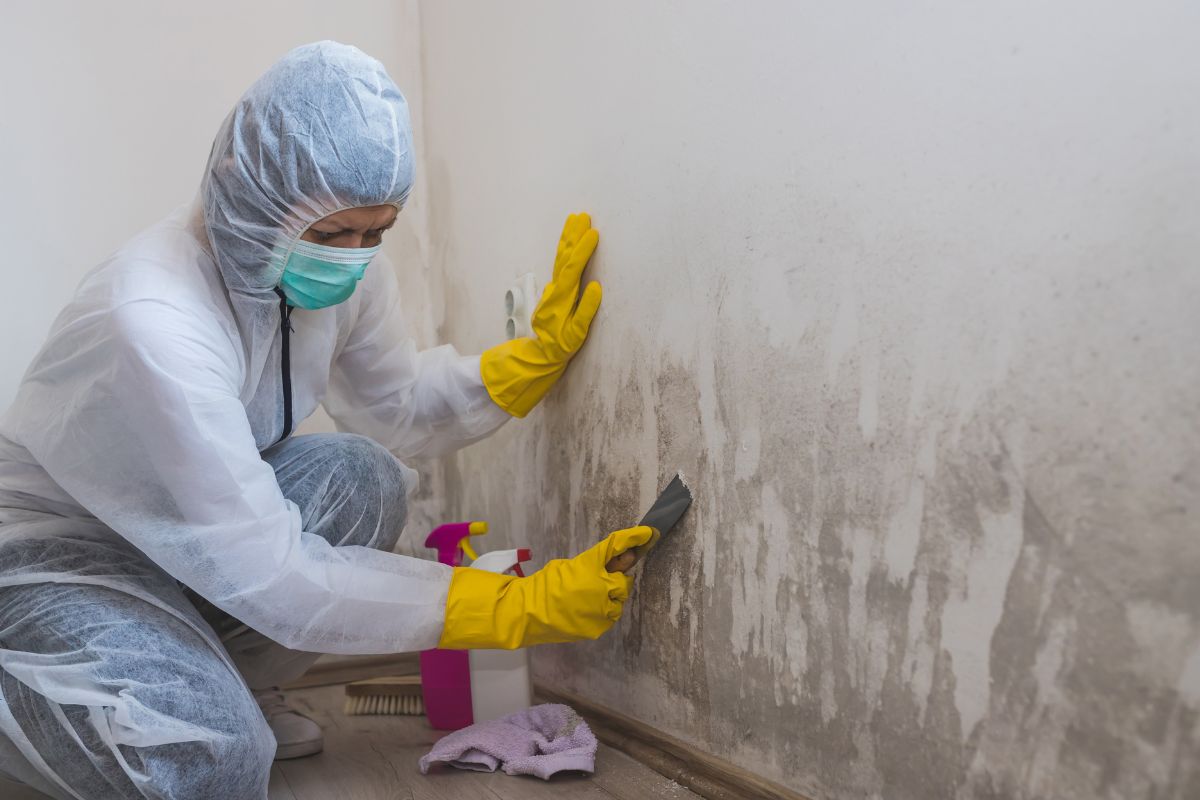  A woman in a white coat and rubber gloves diligently cleans a wall, showcasing her commitment to cleanliness and hygiene.